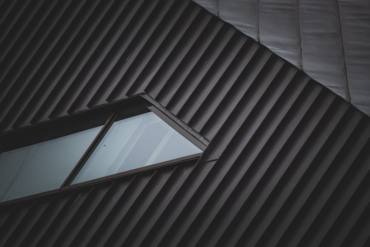 A sleek metal rooftop with a unique window, showcasing modern architectural style and geometric patterns.